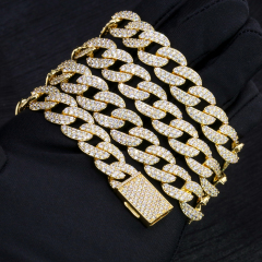 Close-up of a folded 13mm iced out moissanite Cuban link bracelet in gold-plated S925 silver resting on a black glove, showcasing the VVS clarity micro-pave stones and a secure diamond box clasp.