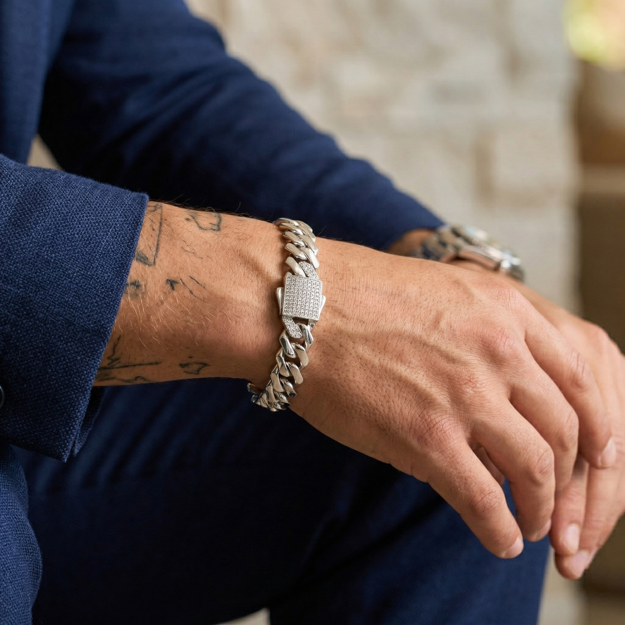 Close-up side profile of a tattooed man wearing a custom iced-out moissanite Cuban link bracelet, revealing the chain's thickness and luster.