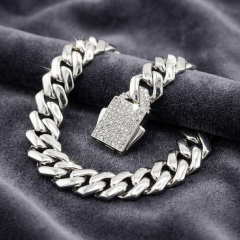 Iced-out Cuban link bracelet resting on grey velvet, highlighting the brilliant moissanite stones and the secure box clasp mechanism.