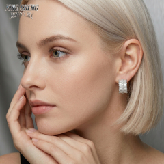 Elegant blonde model wearing Xing Sheng Jewelry custom moissanite hoop earrings, looking to the side against a sleek grey background.