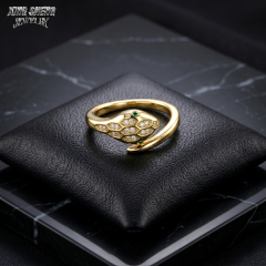 Top-down macro view of the intertwining serpent heads on a black leather cushion, gripping a pristine, colorless round brilliant moissanite with superior light return.
