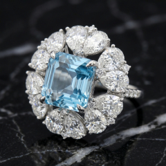 Dramatic close-up of the Asscher cut natural topaz and pear moissanite floral halo ring resting on a luxurious black marble surface, emphasizing gemstone brilliance and fire.