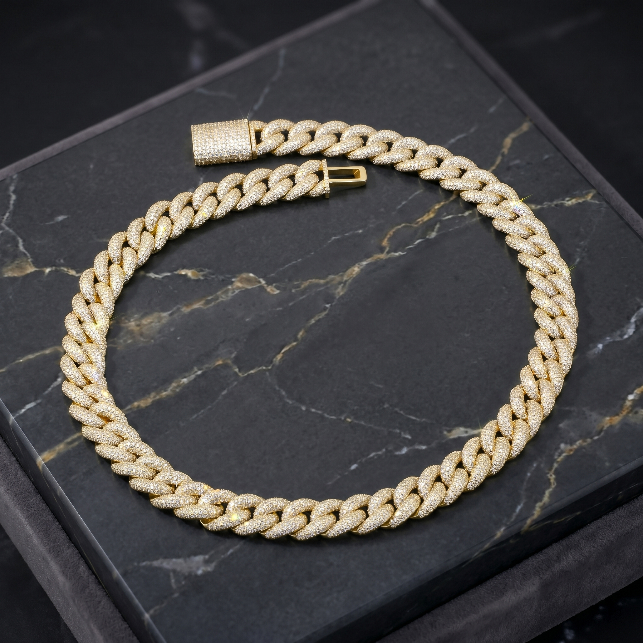 Stunning 16mm iced-out moissanite Cuban chain in gold finish resting on an elegant black marble display surface.