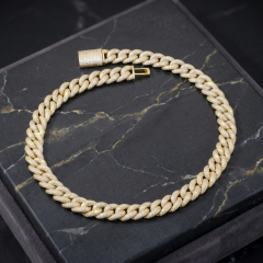 Stunning 16mm iced-out moissanite Cuban chain in gold finish resting on an elegant black marble display surface.