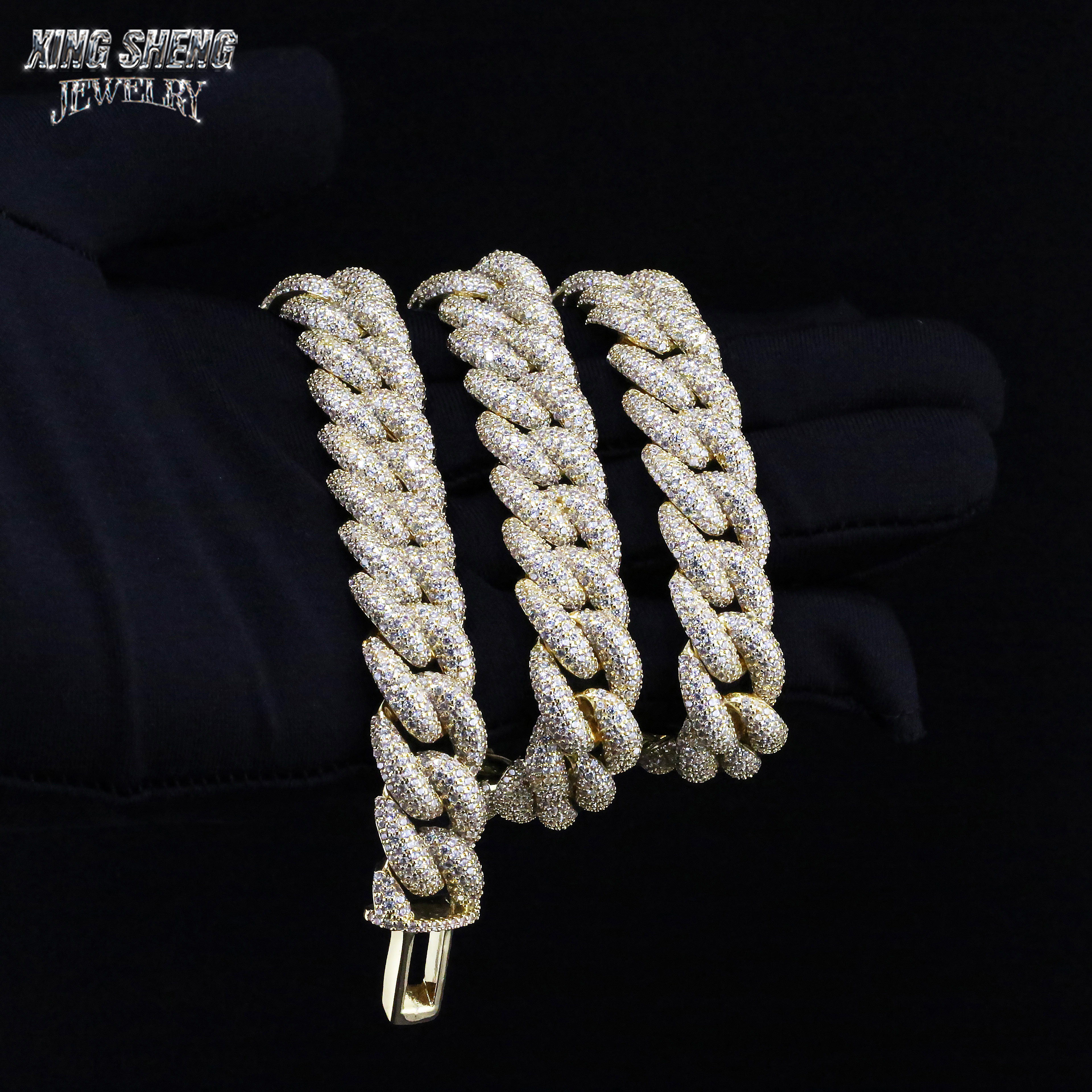 Gloved hand holding a heavy, multiple-layered 16mm iced out moissanite Cuban link chain in yellow gold finish.
