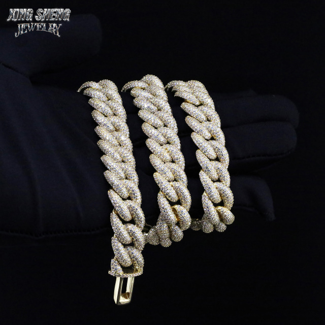 Gloved hand holding a heavy, multiple-layered 16mm iced out moissanite Cuban link chain in yellow gold finish.