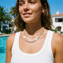 Female model enjoying a sunny day by the pool, wearing a layered 925 silver moissanite tennis necklace that exhibits exceptional rainbow fire and D-color brilliance.