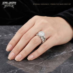 Woman wearing a perfectly matched moissanite engagement ring and link style eternity band resting her hand on dark marble.