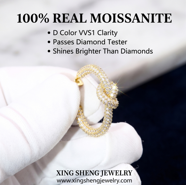 Close up of a gloved hand holding a brilliant D color VVS1 moissanite love knot earring that passes diamond testers and shines brighter than diamonds.