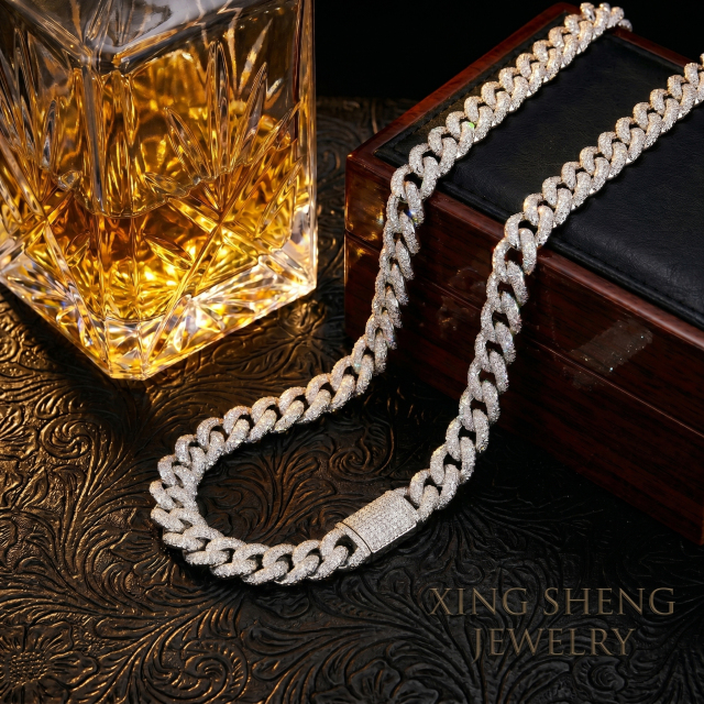 Men's luxury lifestyle shot featuring the 10MM iced out moissanite Cuban chain next to a crystal whiskey decanter and a vintage wooden box.