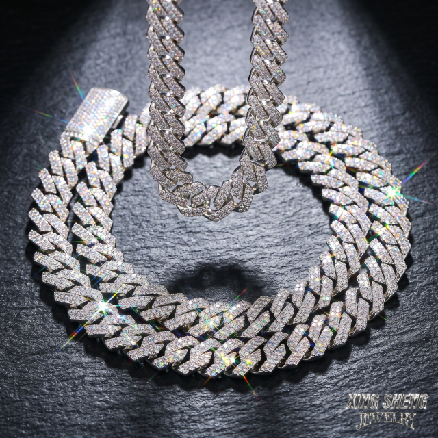 Brilliant optical fire and colorful dispersion shining from a 13MM moissanite Cuban necklace resting on a dark slate background.