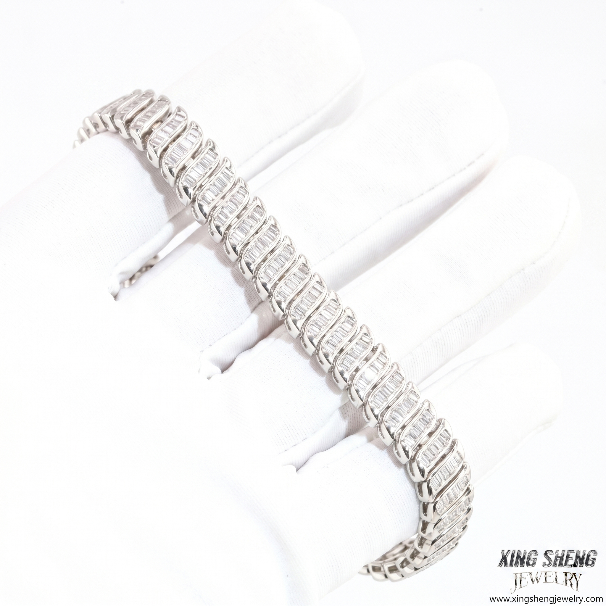 A professional gloved hand inspecting the flawless D-color and VVS clarity of the 8mm baguette moissanite stones on a sterling silver bracelet.