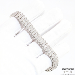 A professional gloved hand inspecting the flawless D-color and VVS clarity of the 8mm baguette moissanite stones on a sterling silver bracelet.