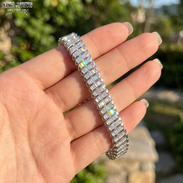 The 8mm baguette moissanite bracelet held in a hand outdoors, capturing the incredible optical dispersion and rainbow fire under natural sunlight.