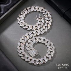 A long 14mm iced out moissanite Cuban link chain gracefully draped in an S-shape on a metallic surface, highlighting the seamless soldered links and the 0.3-micron rhodium white gold finish.