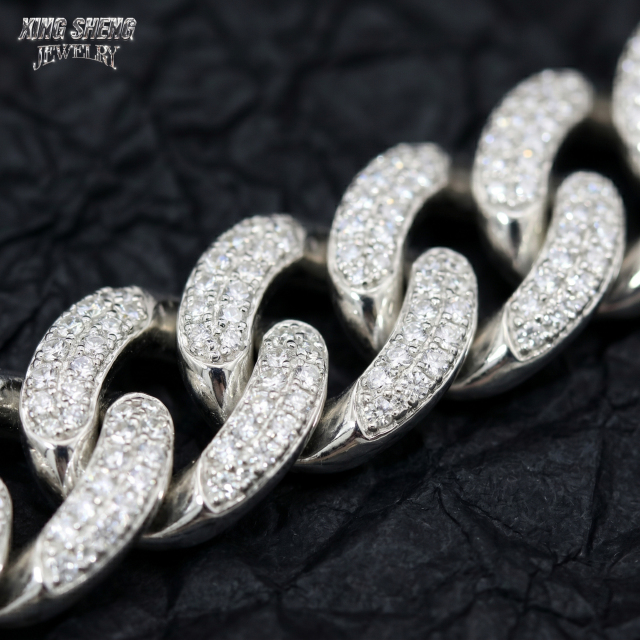 Macro photography of flawless VVS D-color moissanite stones securely set in a 10mm white gold Cuban link chain, highlighting excellent cut and professional 4-prong jewelry craftsmanship.