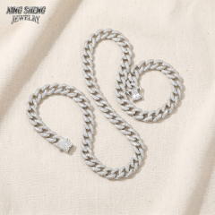 A matching set of 10mm white gold plated moissanite Cuban link necklace and bracelet crafted from S925 silver, displayed on a textured linen background highlighting the secure box clasp.