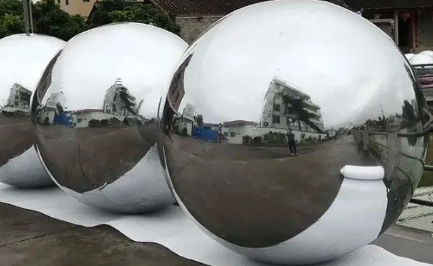 inspector checking seams and chrome surface on an inflatable mirror ball; macro seam detail, soft diffused light, studio neutral background, ultra-gloss finish, product QC documentary style
