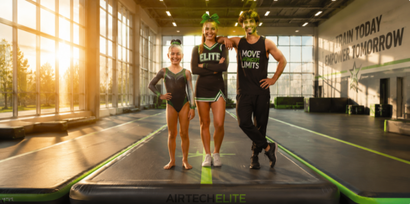 Proud, confident young athletes standing on a premium inflatable air track inside a sunlit training center.