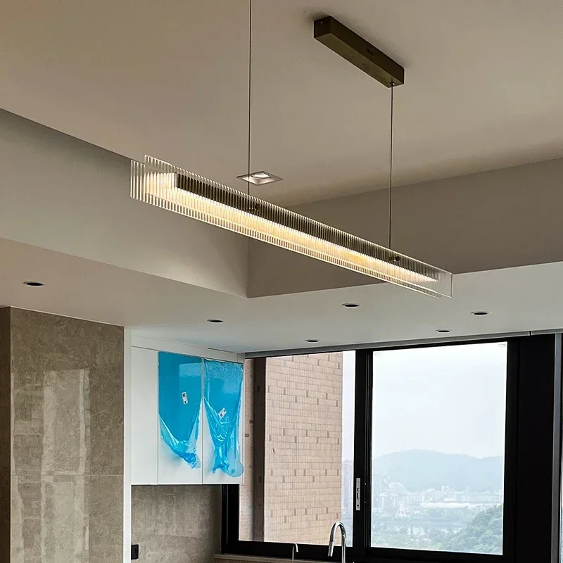 Minimalist LED linear pendant lamp hanging over a wooden dining table