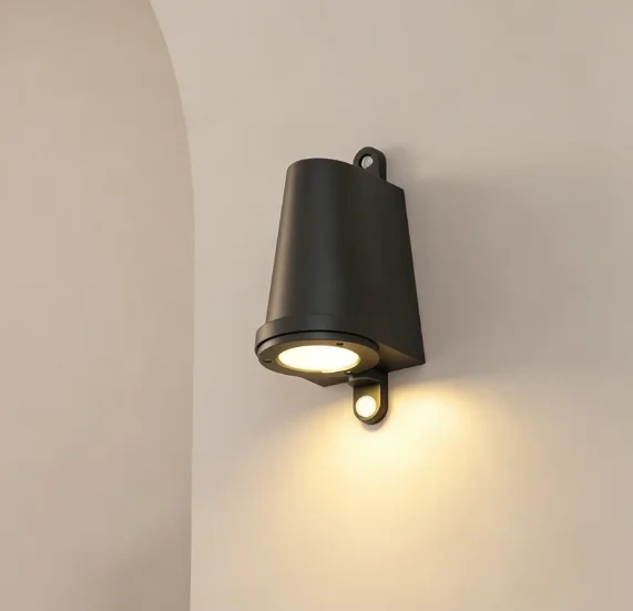 Matte black wall sconce casting warm light onto a pale wall