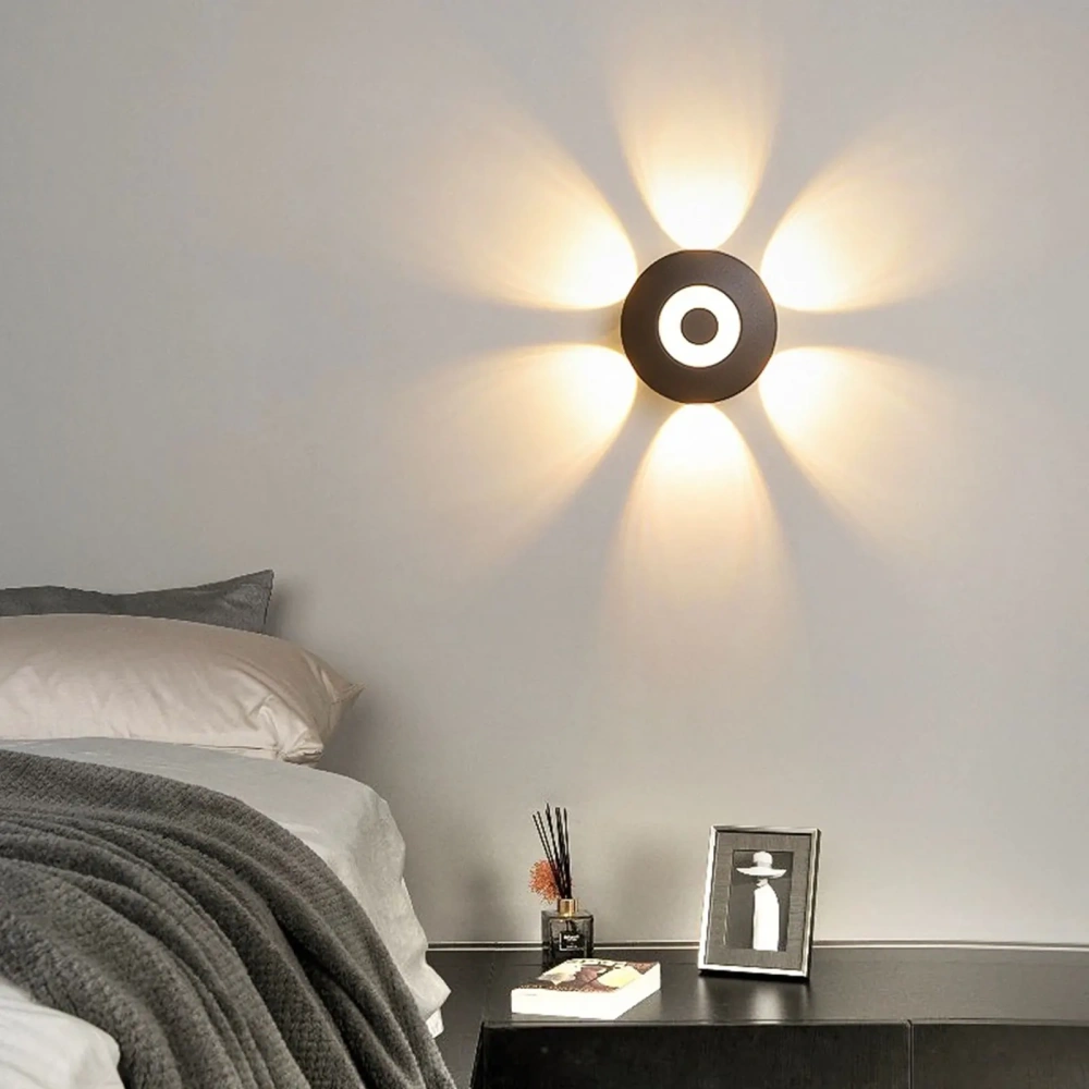 Black LED wall light with an illuminated ring and warm beams beside a bed