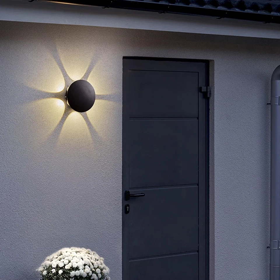 Round black LED wall light creating warm decorative beams beside a doorway