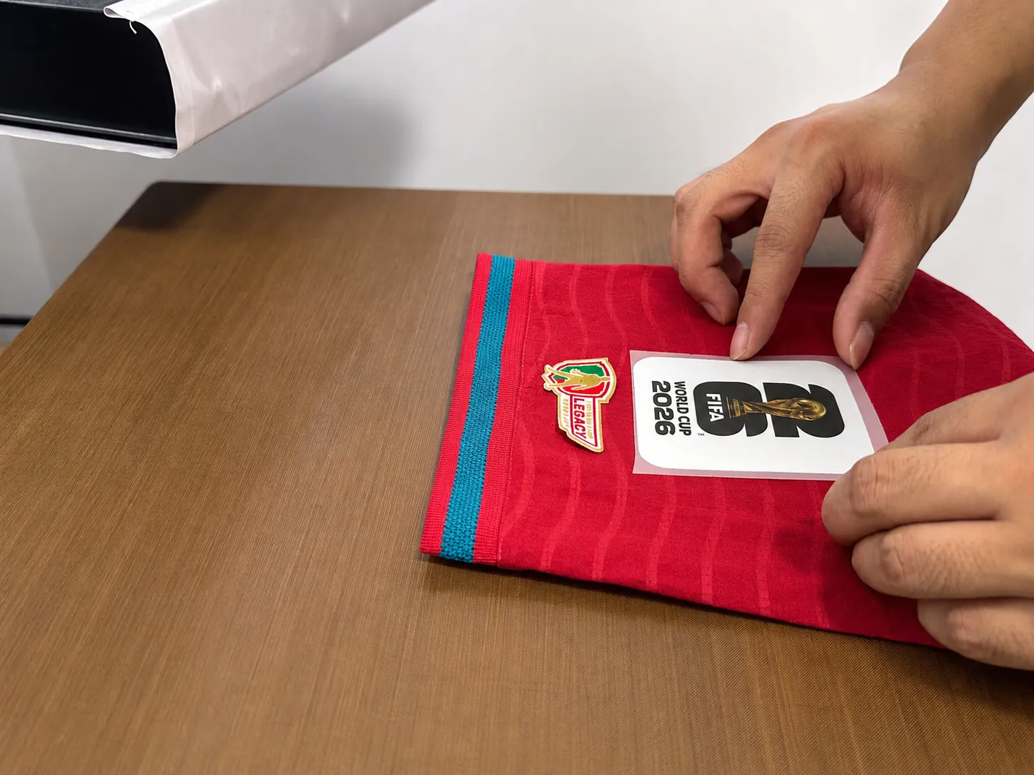 Sleeve patch being positioned on a customized football jersey
