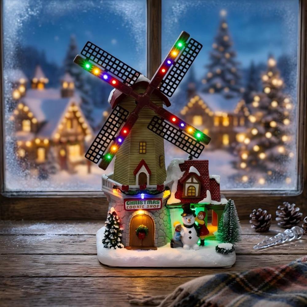 Lighted Christmas village windmill cookie shop figurine with colorful LEDs on a rustic wooden windowsill at twilight.