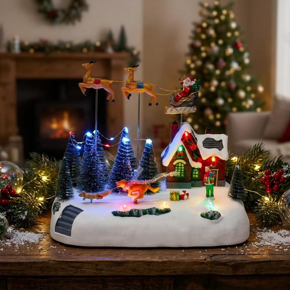 Animated Christmas village with Santa sleigh flying over a snowy house on a cozy wooden table.