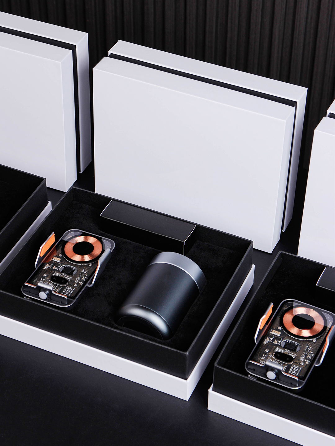 White gift boxes containing a transparent-front phone holder and a dark cylindrical accessory