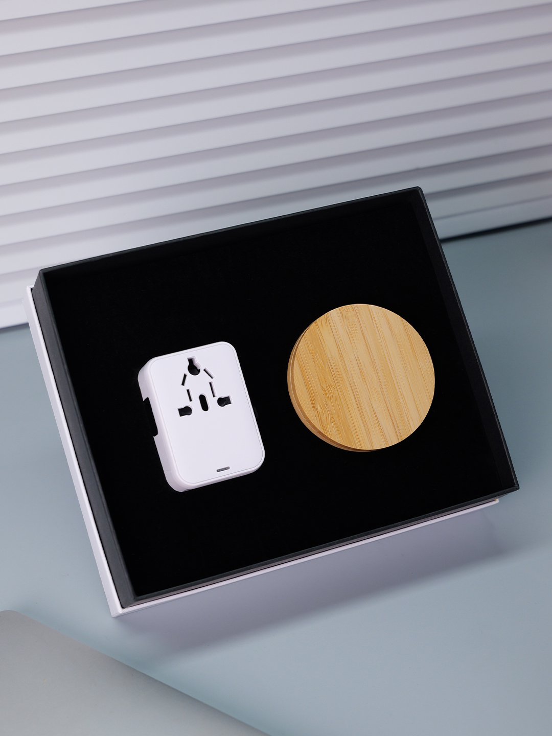 White travel adapter and round wood-look accessory case in a fitted gift box