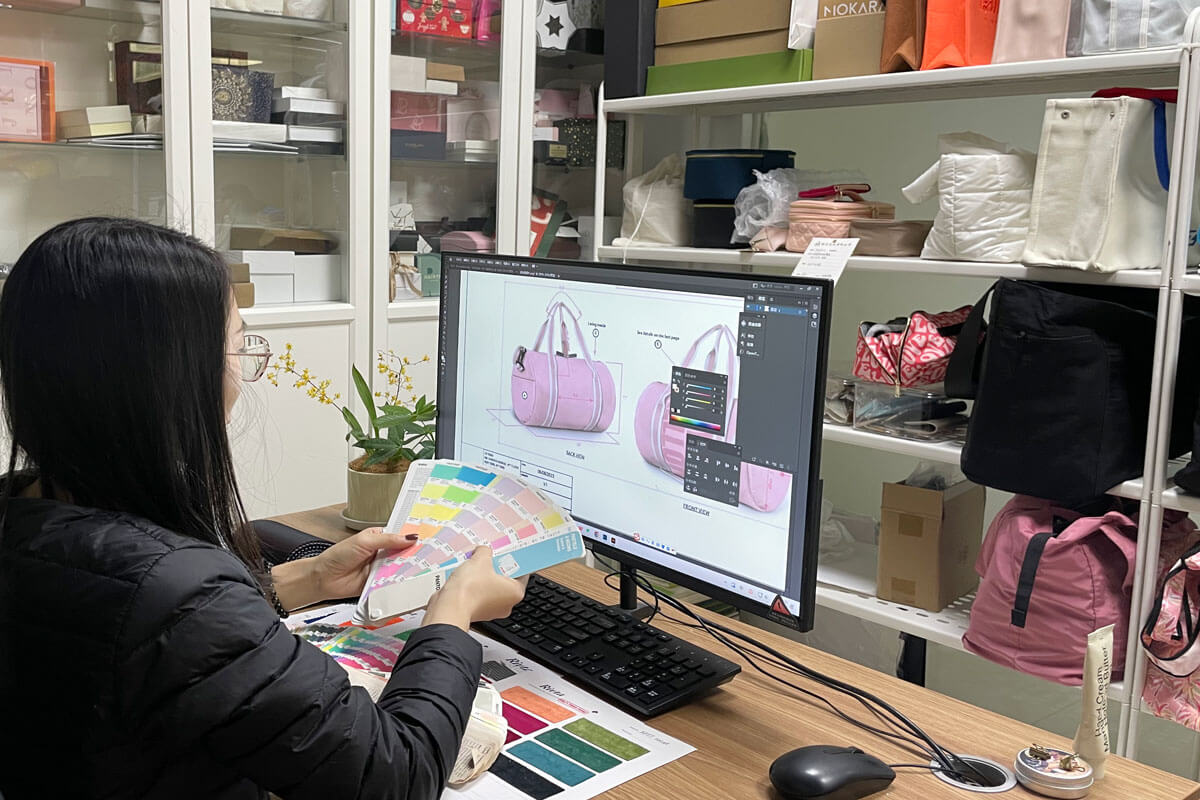 A designer looking at a Pantone color chart next to swatches of recycled fabric in various custom shades.