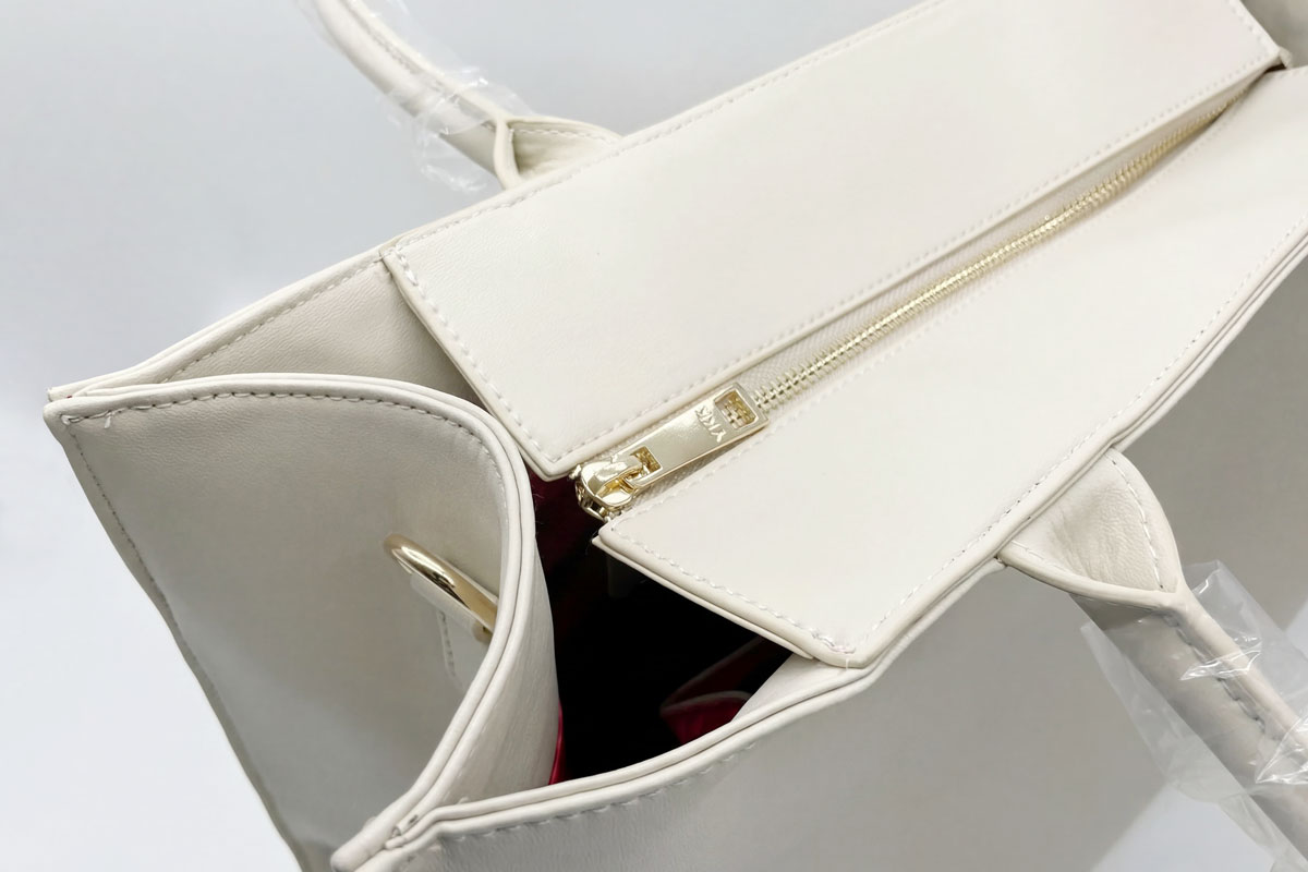 Detail shot of a high-quality metal zipper with a custom branded pull tab on a textured vegan leather bag.