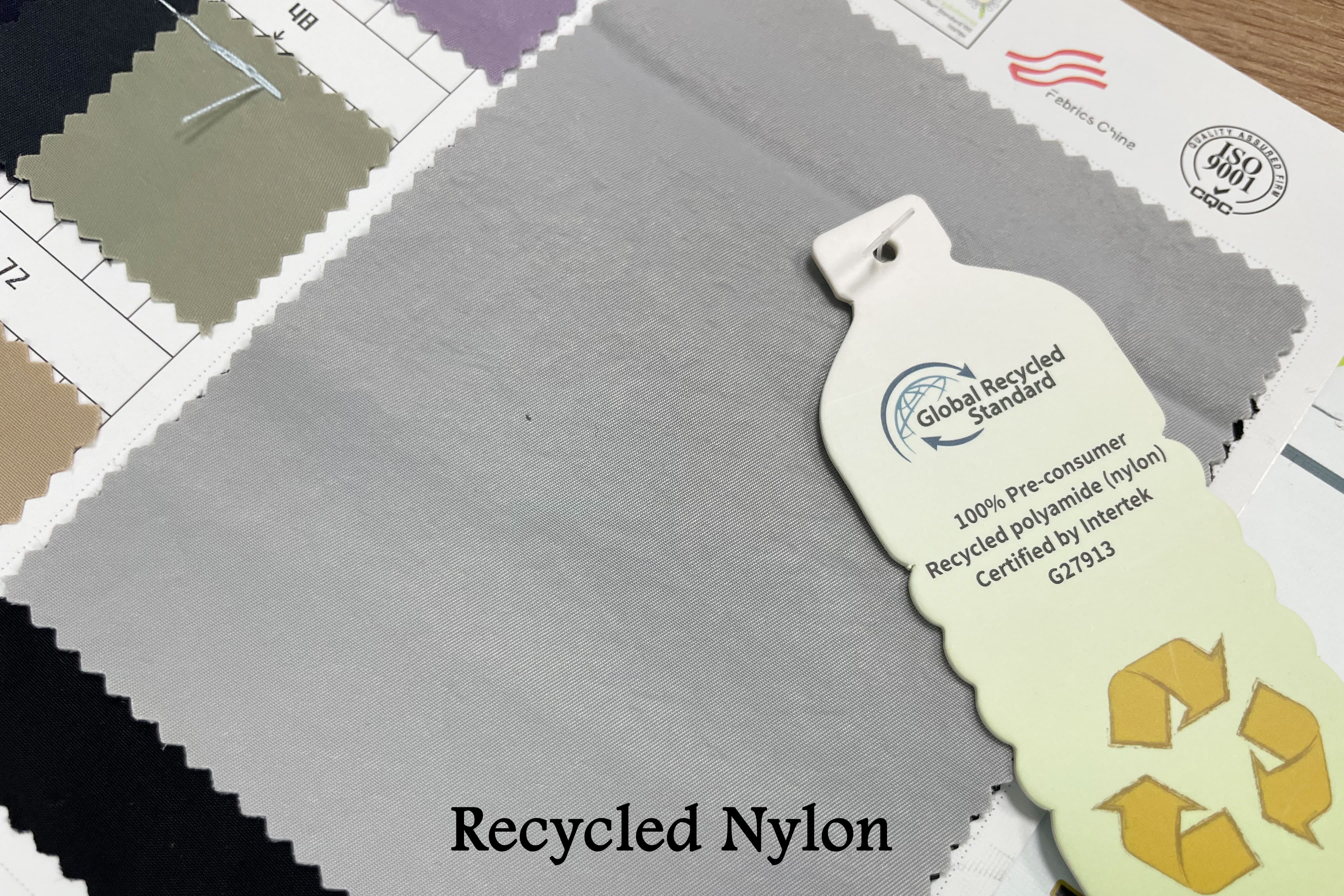 Close-up macro shot of Rivta's Recycled Nylon fabric texture, showing the high-quality weave, perhaps with a GRS certificate in the background.