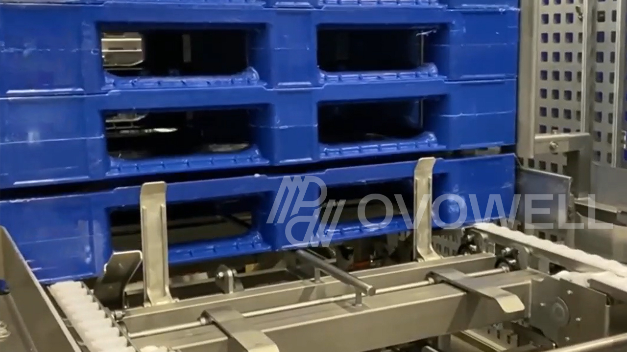 Blue plastic crates entering an automatic washing machine