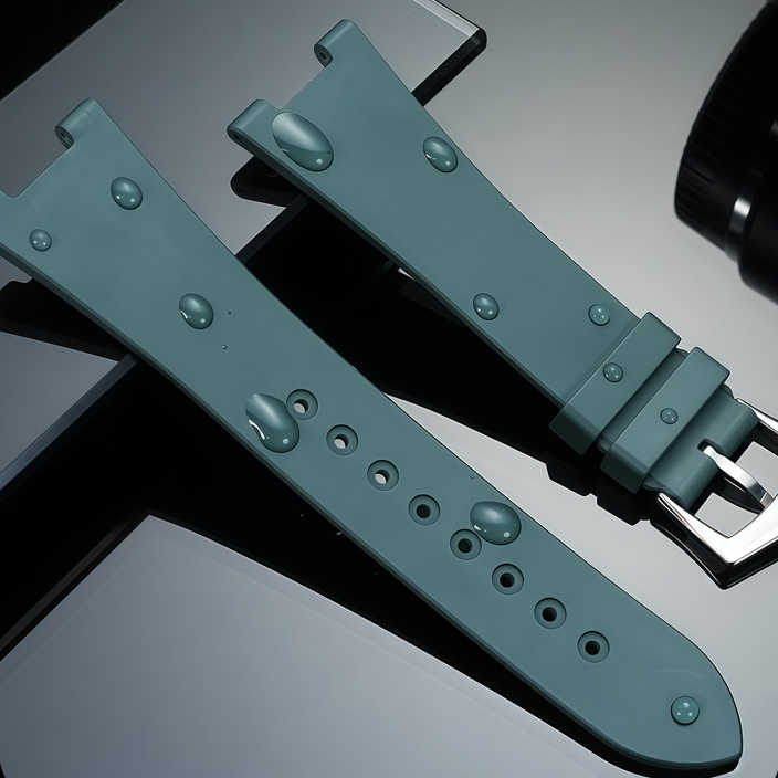 Teal-green rubber straps with rivet studs and polished steel buckle