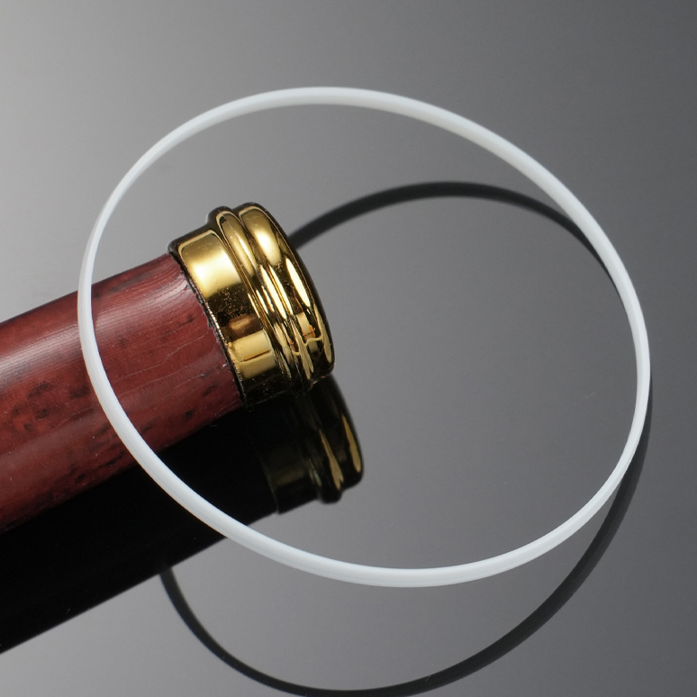 White gasket ring with wood-grain object and gold-tone cap