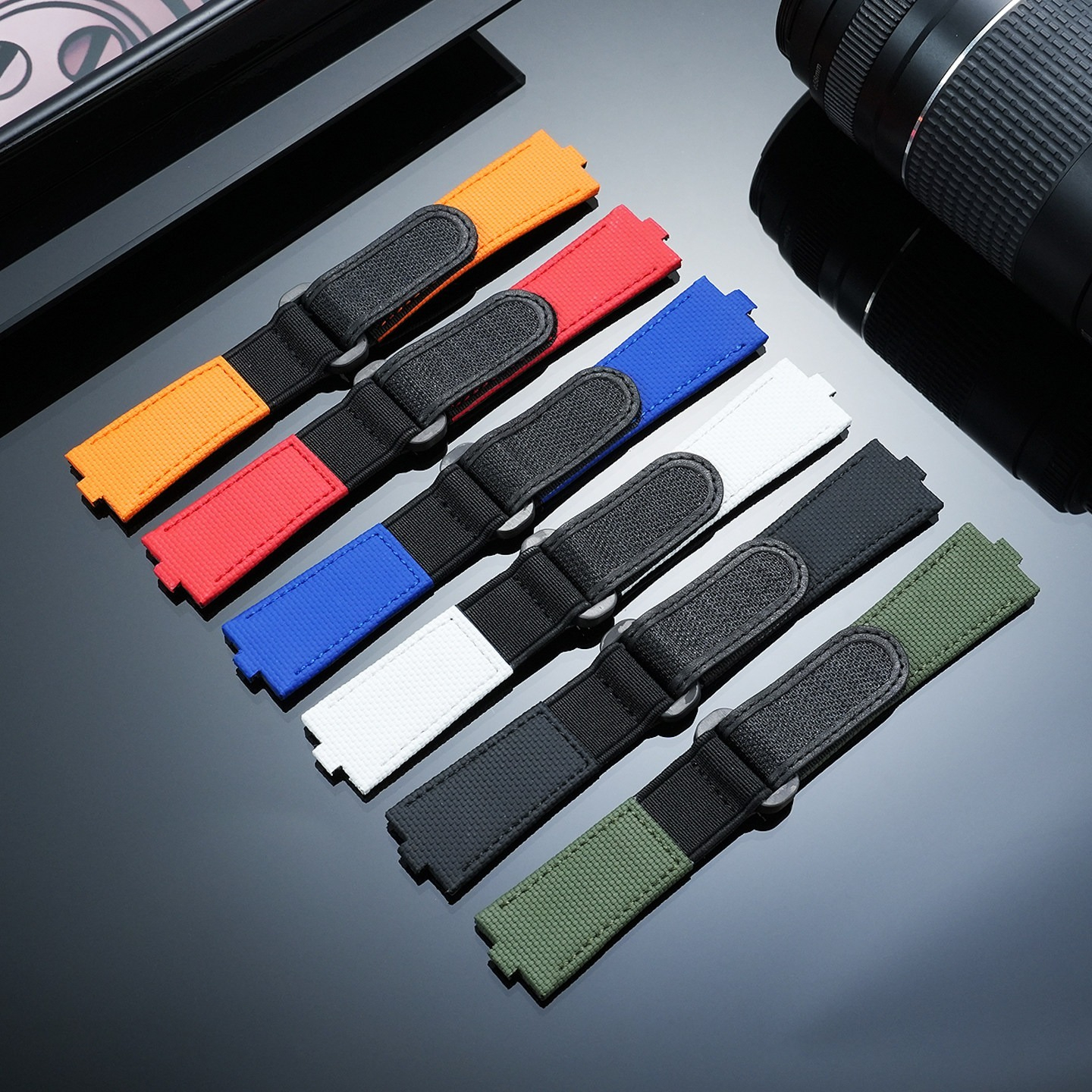 Six watch straps in different colours fanned out on a dark surface