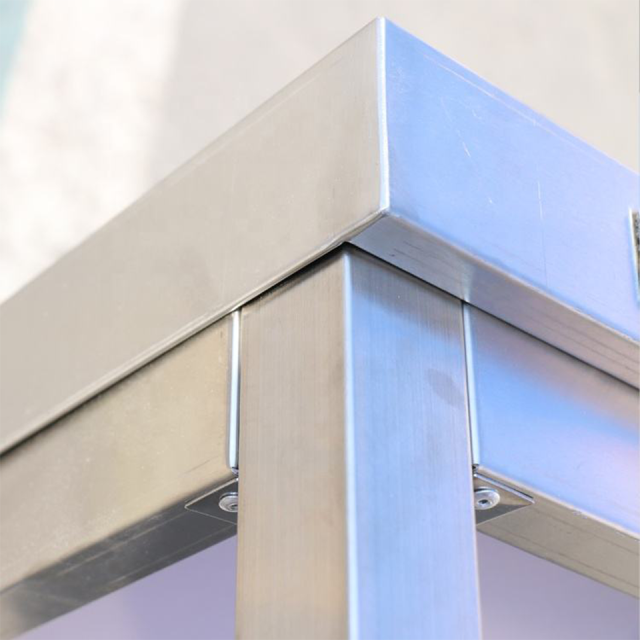 Mesa de trabalho de aço inoxidável de dois níveis com painel traseiro para cozinhas profissionais.