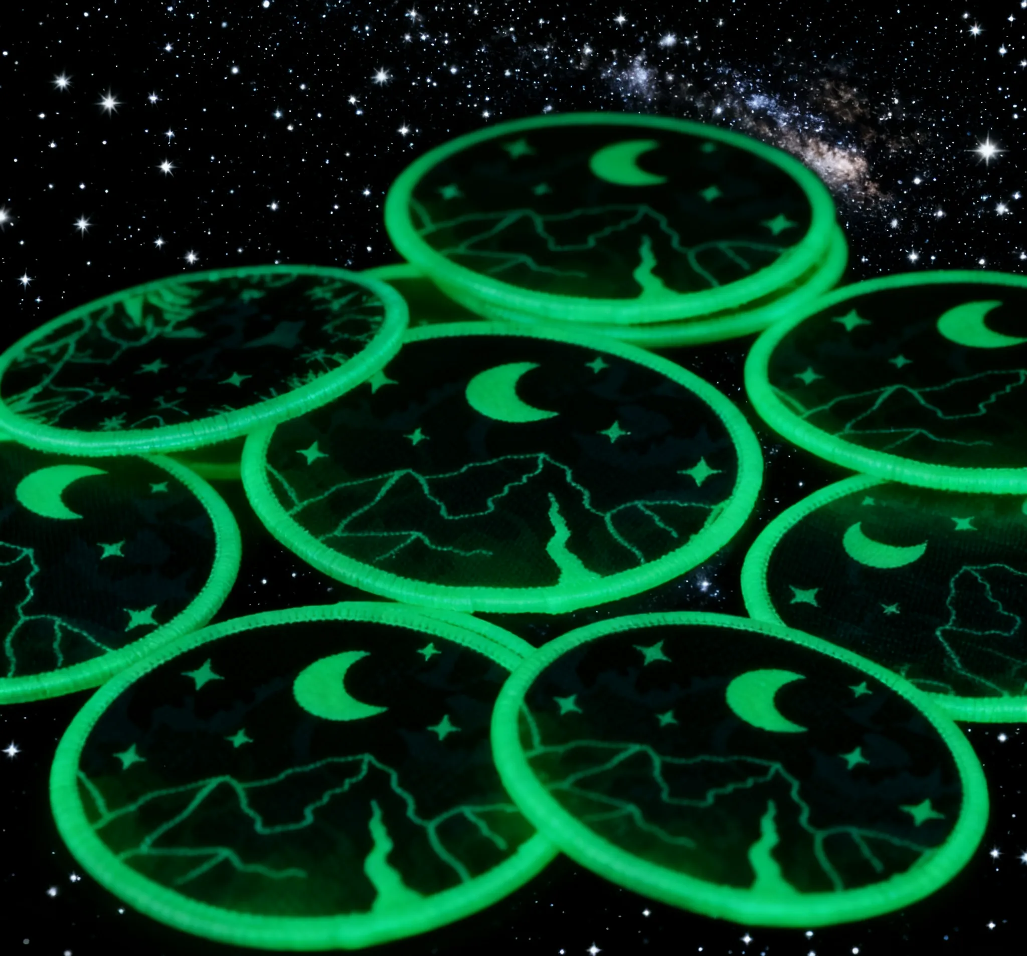 Glow-in-the-dark embroidered patches featuring moon, stars, and mountain designs, showcasing luminous details for nighttime visibility and unique apparel customization.