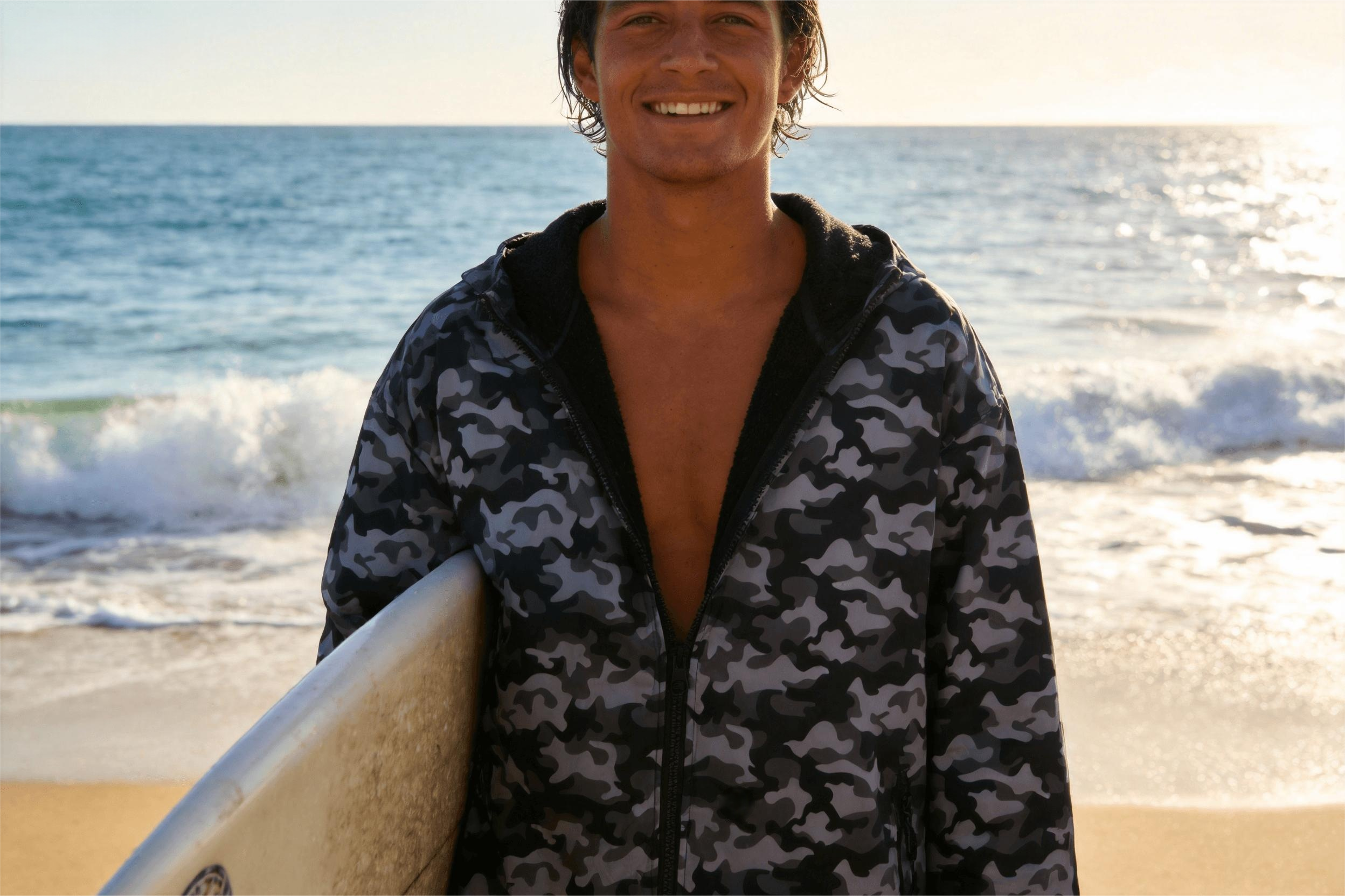 Surfer using camouflage changing robe after surfing