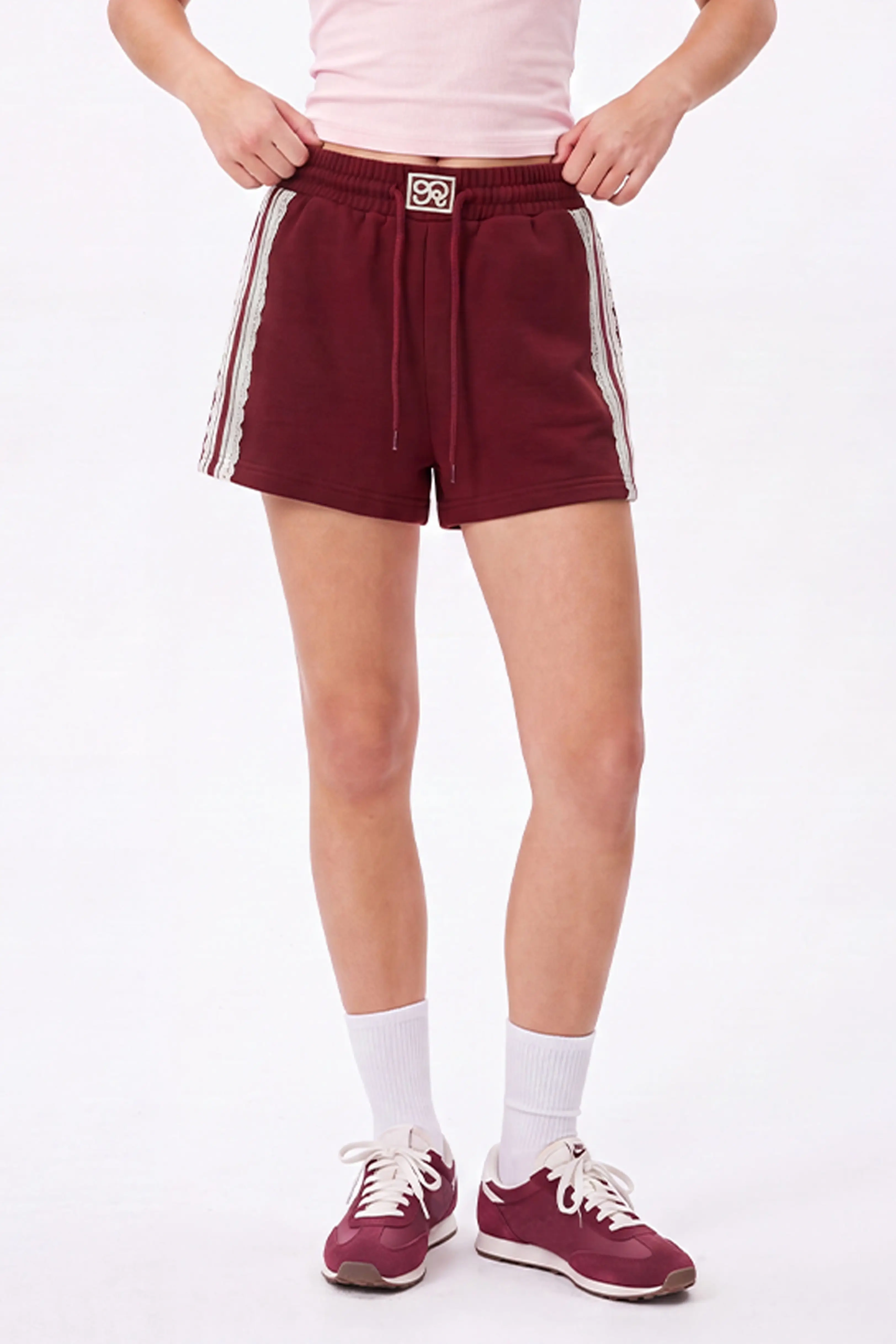 Front view of burgundy cotton sweat shorts with lace trim detail and elastic waistband