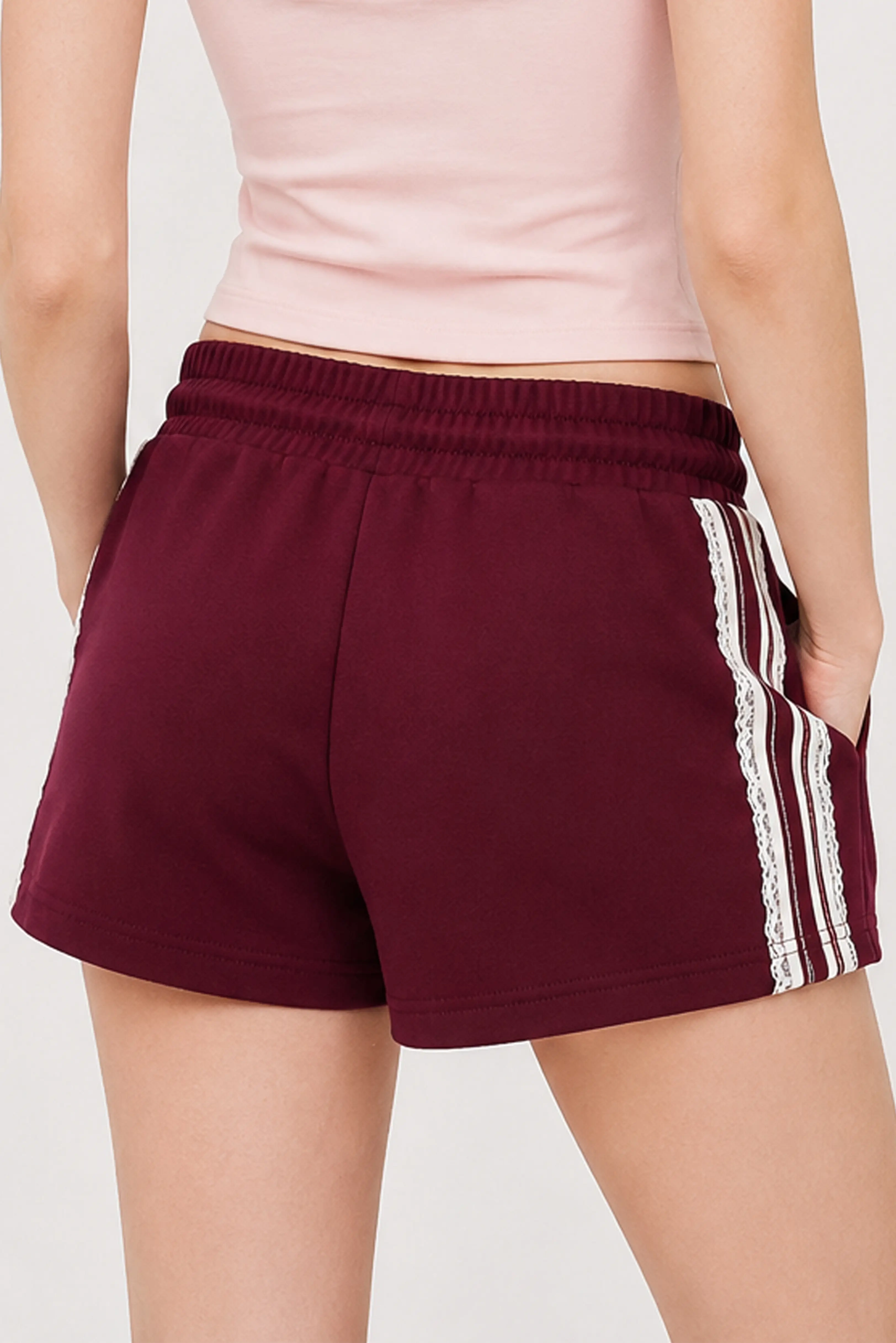 Close-up view of burgundy cotton sweat shorts with delicate side lace trim detail