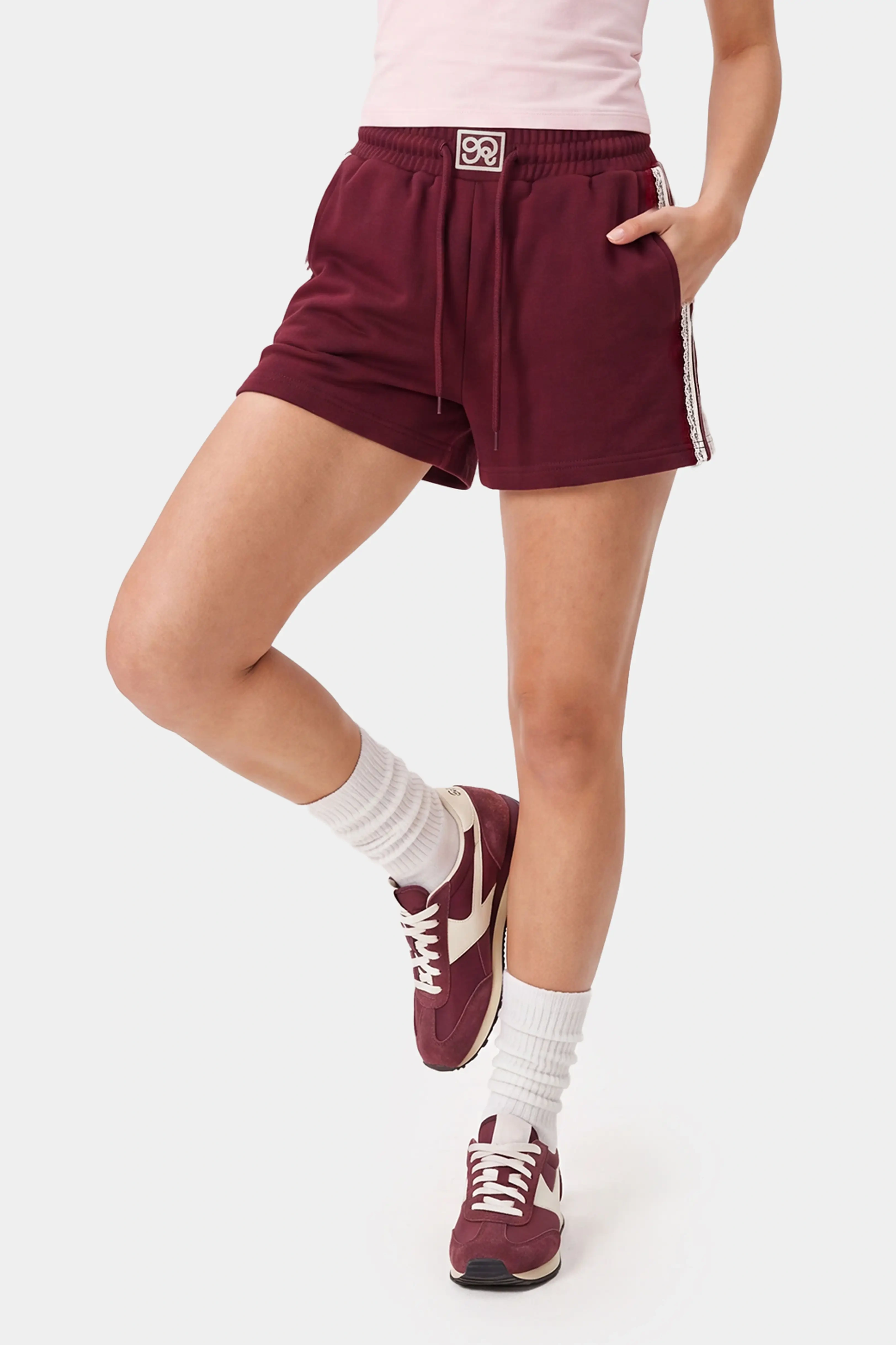 Woman styling burgundy lace trim sweat shorts for casual athleisure wear