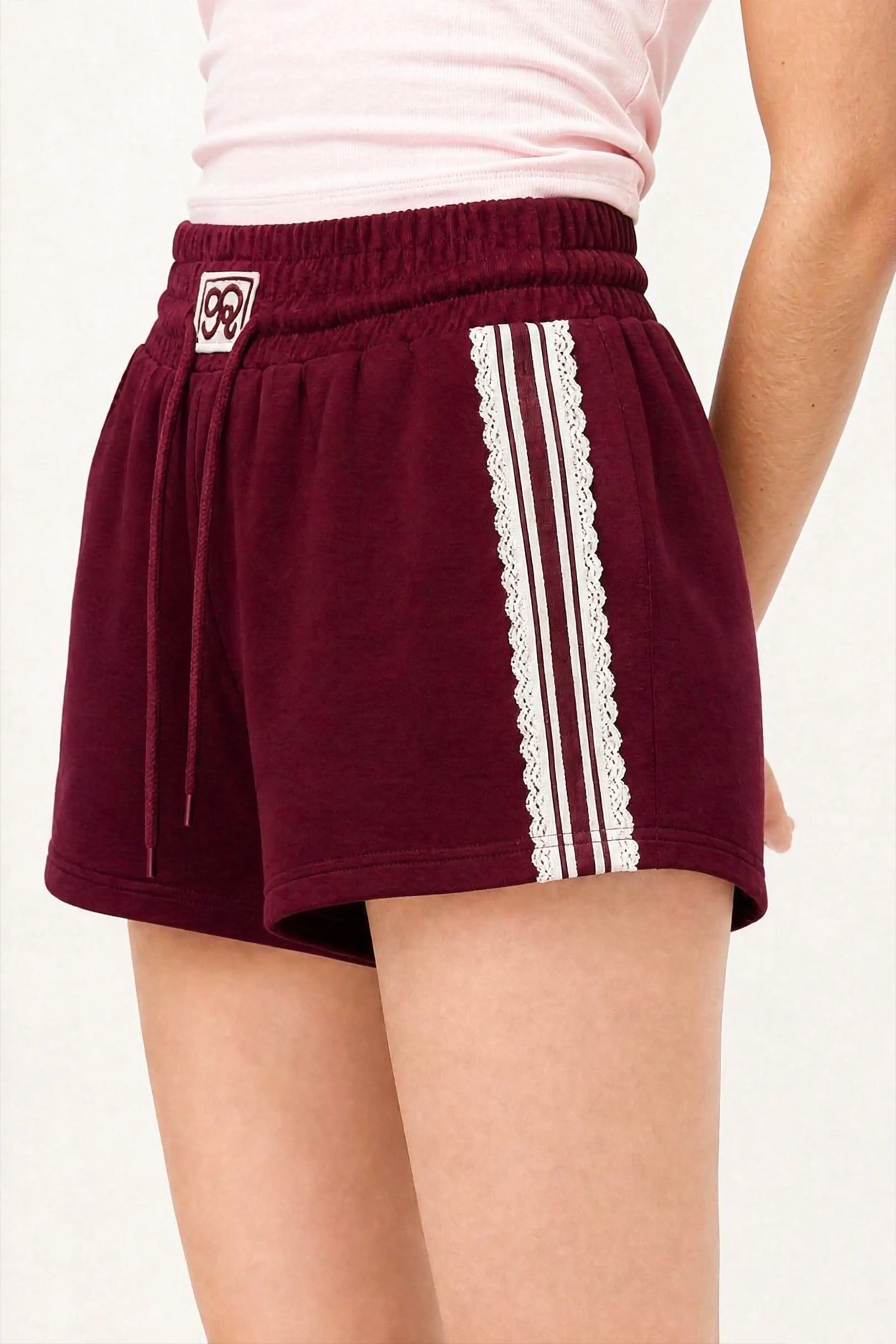 Side view of burgundy lace trim cotton sweat shorts with feminine sporty design