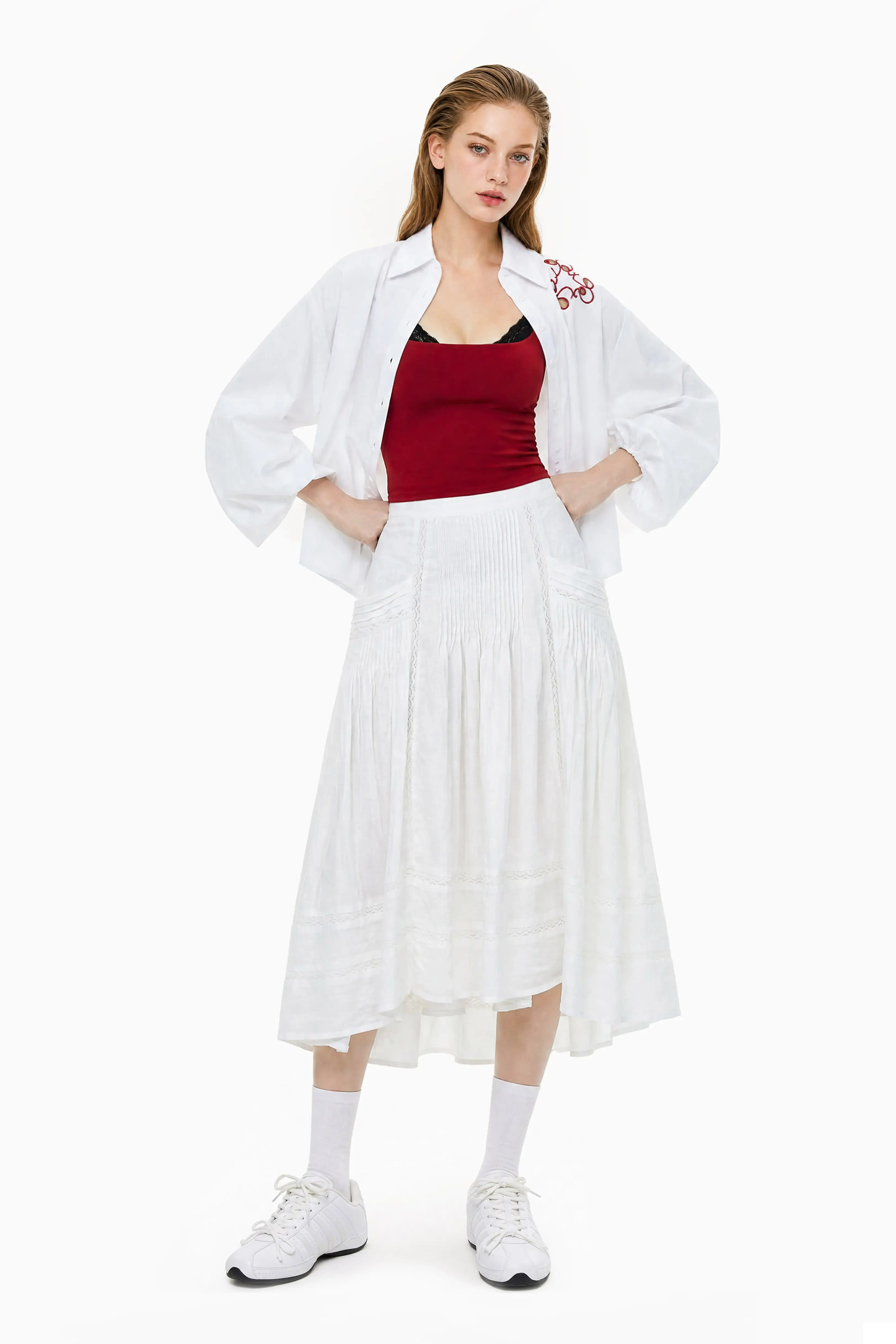 Full body shot of a model wearing an A-line white midi skirt paired with a red top and a white unbuttoned shirt.