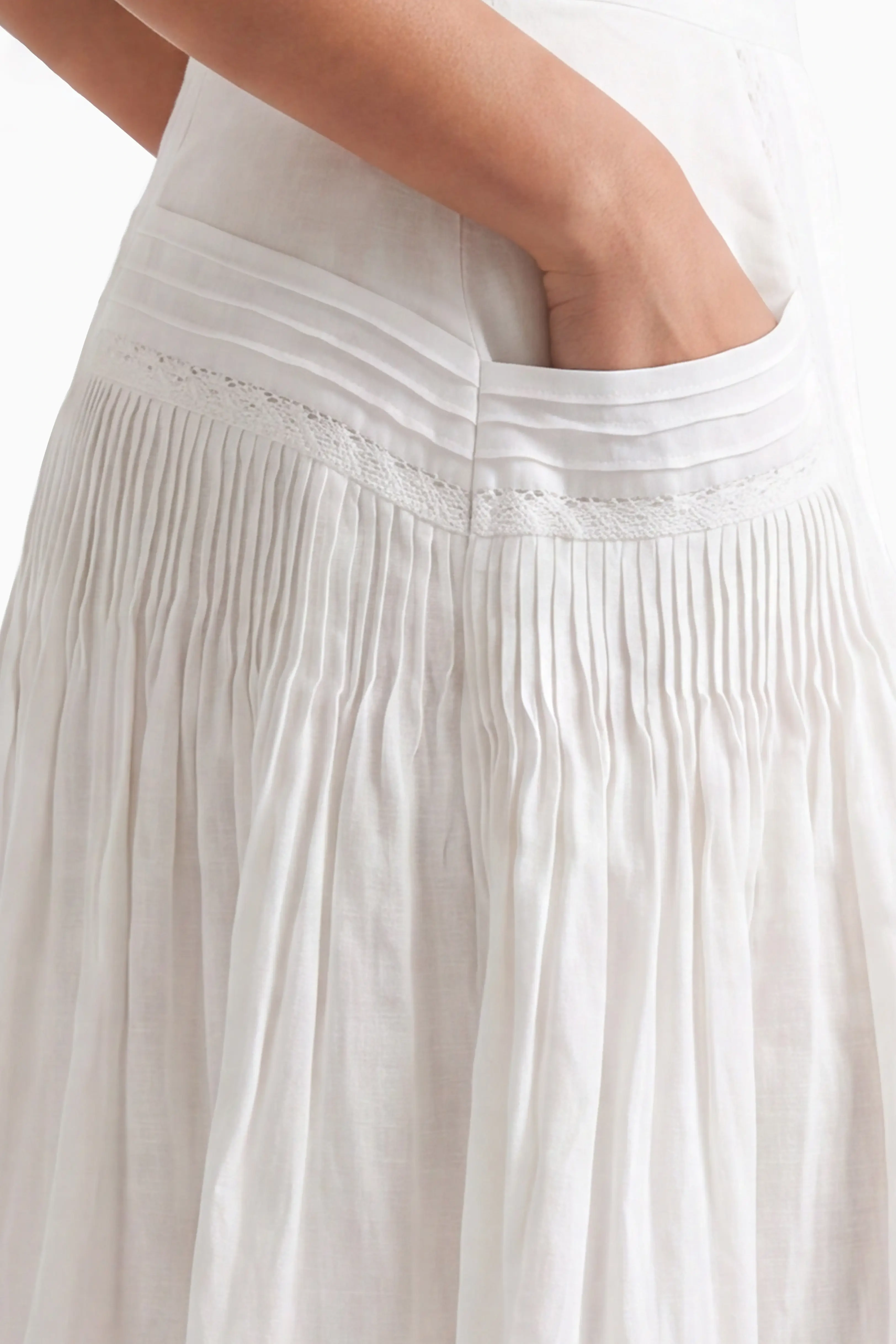 Close-up view showing the side pocket design and vertical pleated pleats on the upper panel of the white midi skirt.