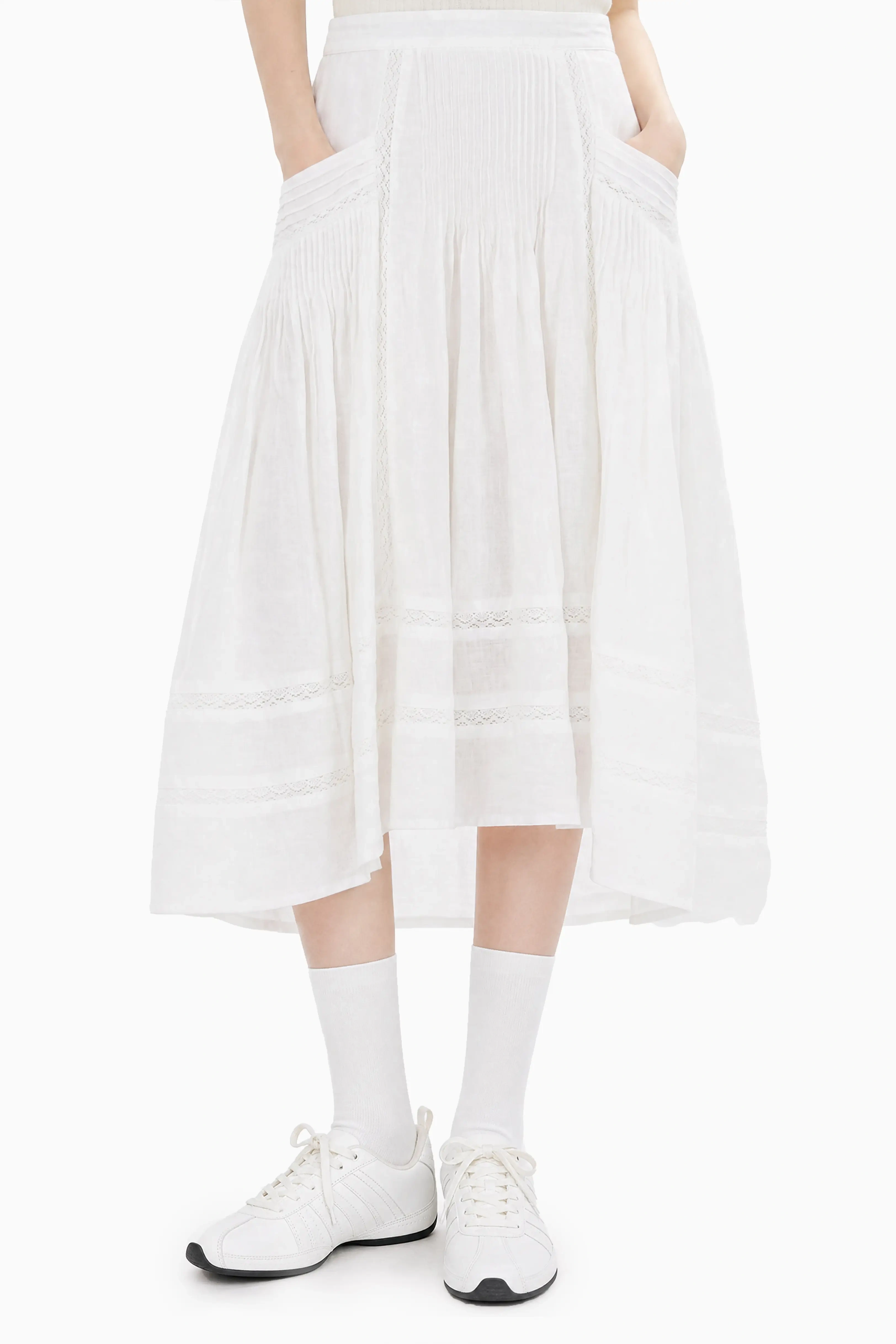 Front three-quarter angle view of a model presenting the fit and flared silhouette of a white midi skirt with side pockets.