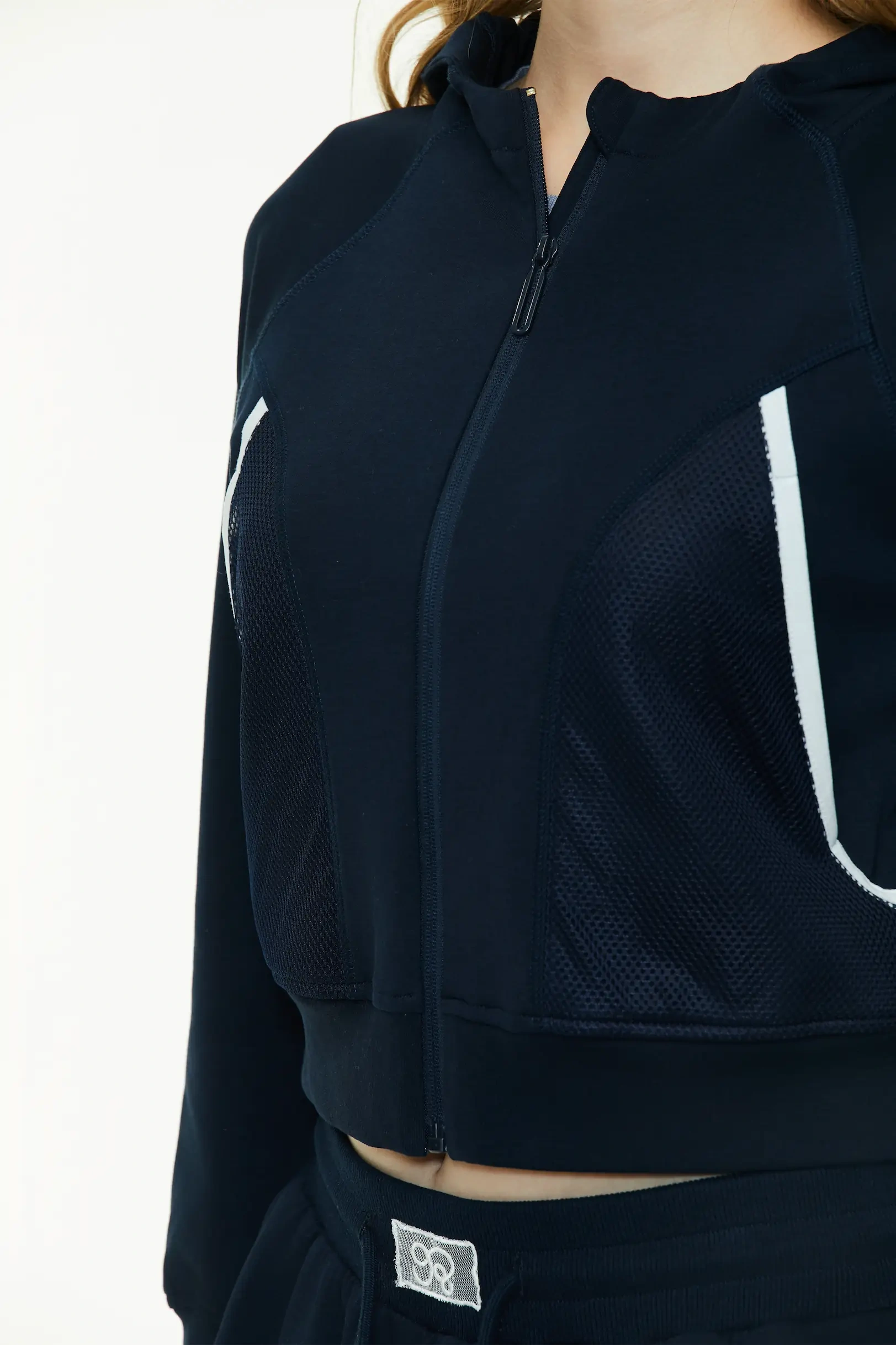 Close-up view highlighting the front zipper, chest seam structure, and white contrast stripe design on the navy blue cropped hoodie.